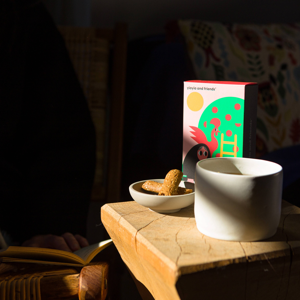 Forager Provisions LTD Mandarin Biscuits in a colourful box next to a small bowl of biscuits and a white ceramic mug.