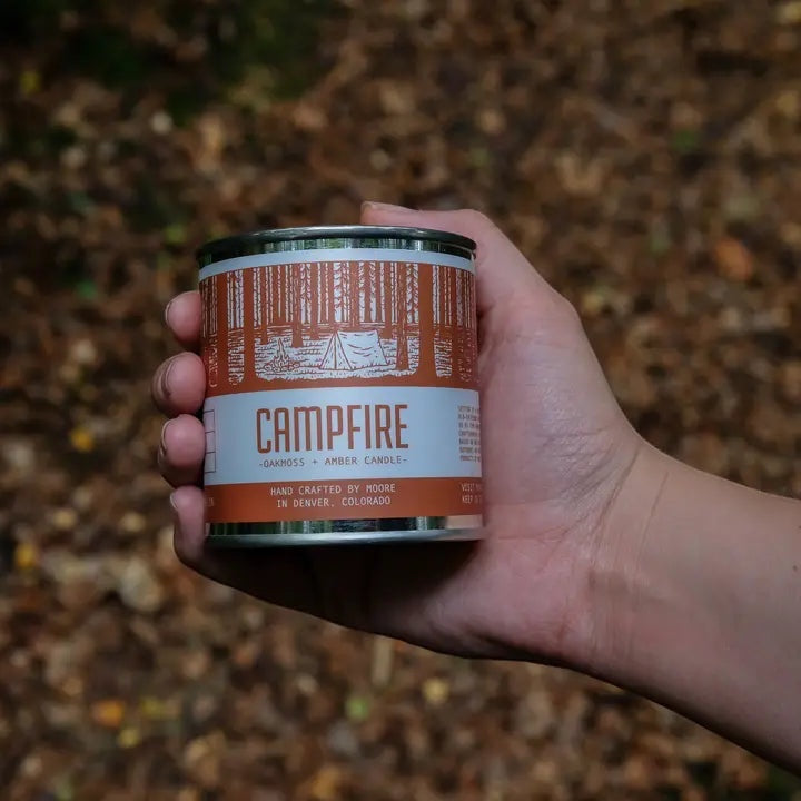 Forager Provisions LTD Moore Collection Campfire soy wax candle in a reusable metal tin held in a hand outdoors