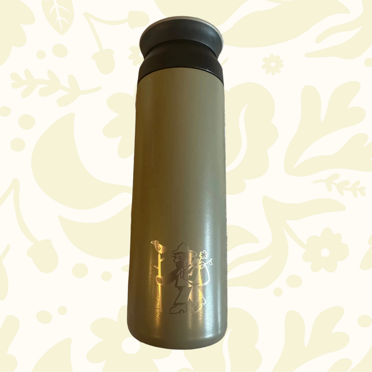 Forager Provisions Travel Mug in Mossy Stone, gold Japanese script, black lid on cream floral background. Eco premium mug.