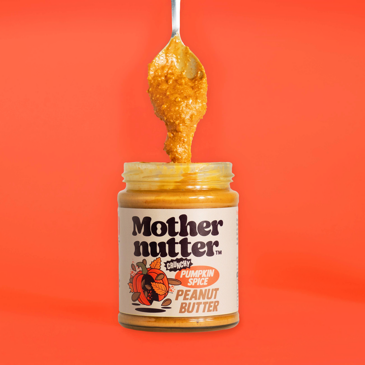 Forager Provisions LTD Mothernutter crunchy pumpkin spice peanut butter in a glass jar with a spoonful held above.