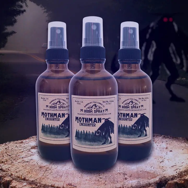 Forager Provisions LTD Wanderlust Folk Mothman room spray bottles with forest and cryptid label on a tree stump.