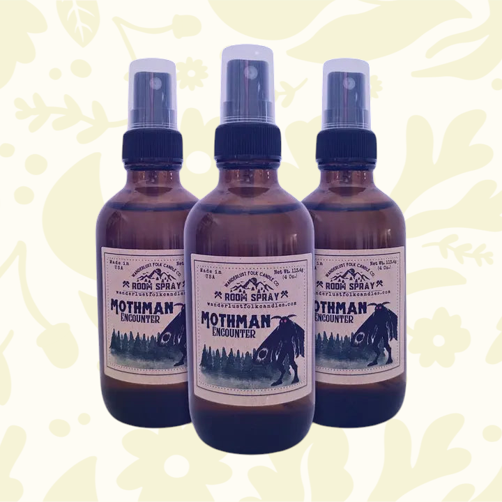 Forager Provisions LTD Wanderlust Folk Mothman room spray bottles with forest and cryptid label on a wooden stump.