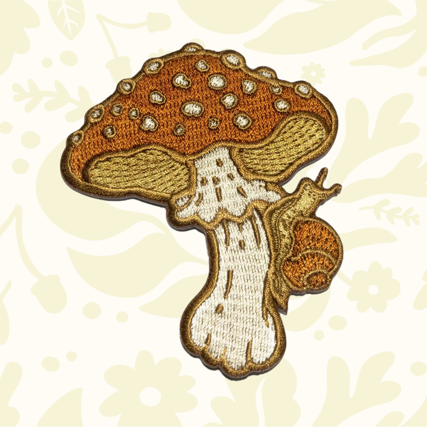 Forager Provisions LTD mustard and white embroidered iron-on patch featuring a detailed mushroom and a small snail.