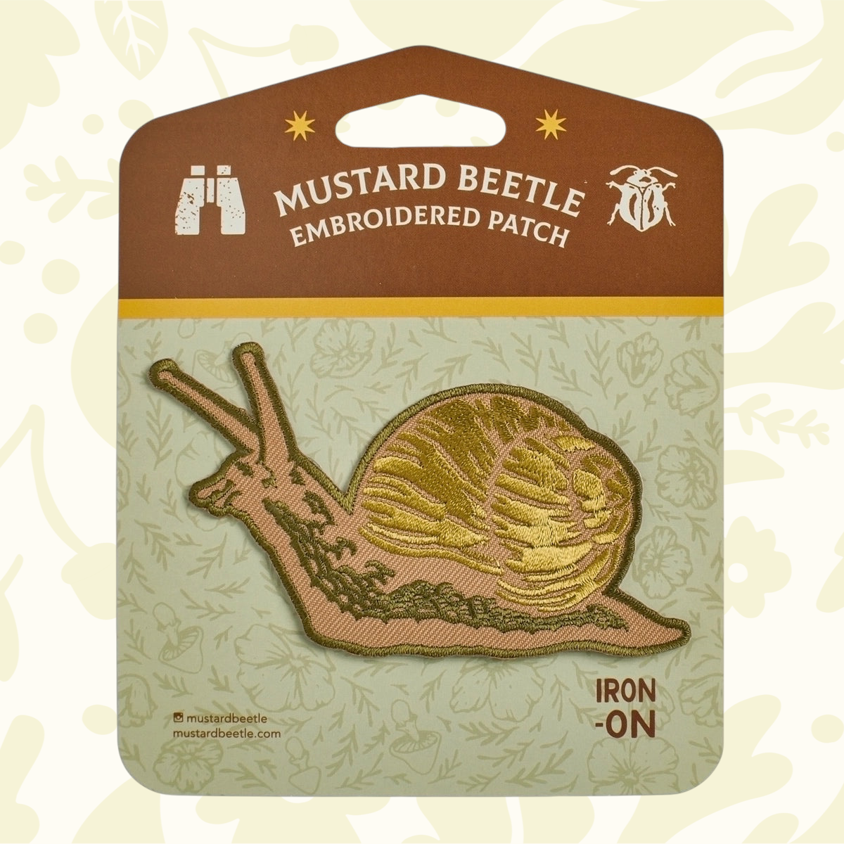 Forager Provisions LTD Mustard Beetle embroidered snail iron-on patch with detailed golden-brown stitching on card.