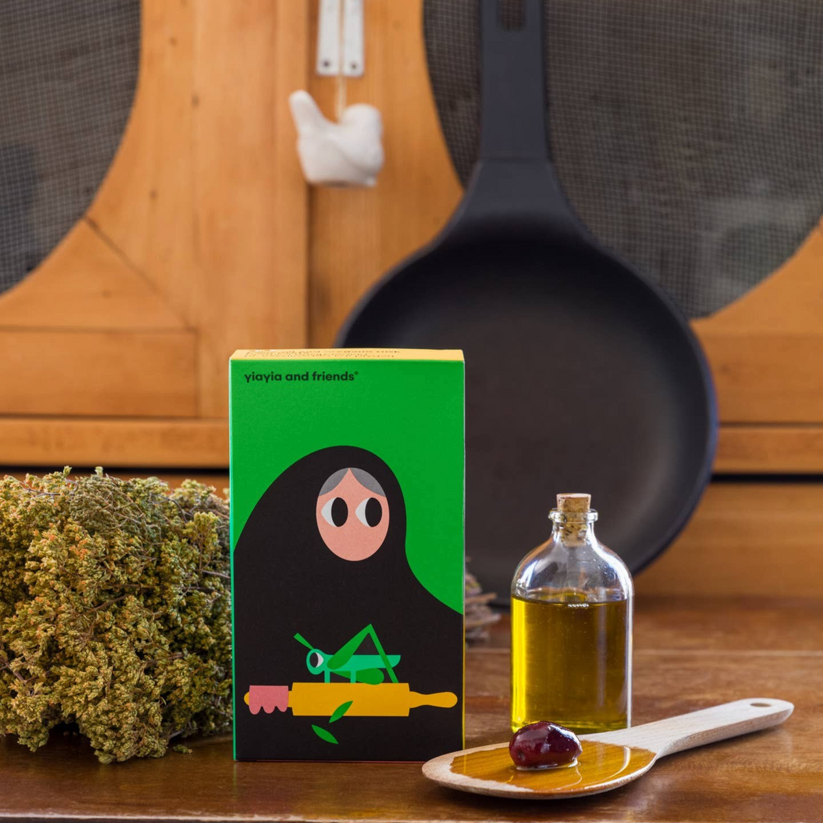 Forager Provisions LTD olive oil and oregano rusks box with dried herbs, olive oil bottle, and wooden spoon on table.