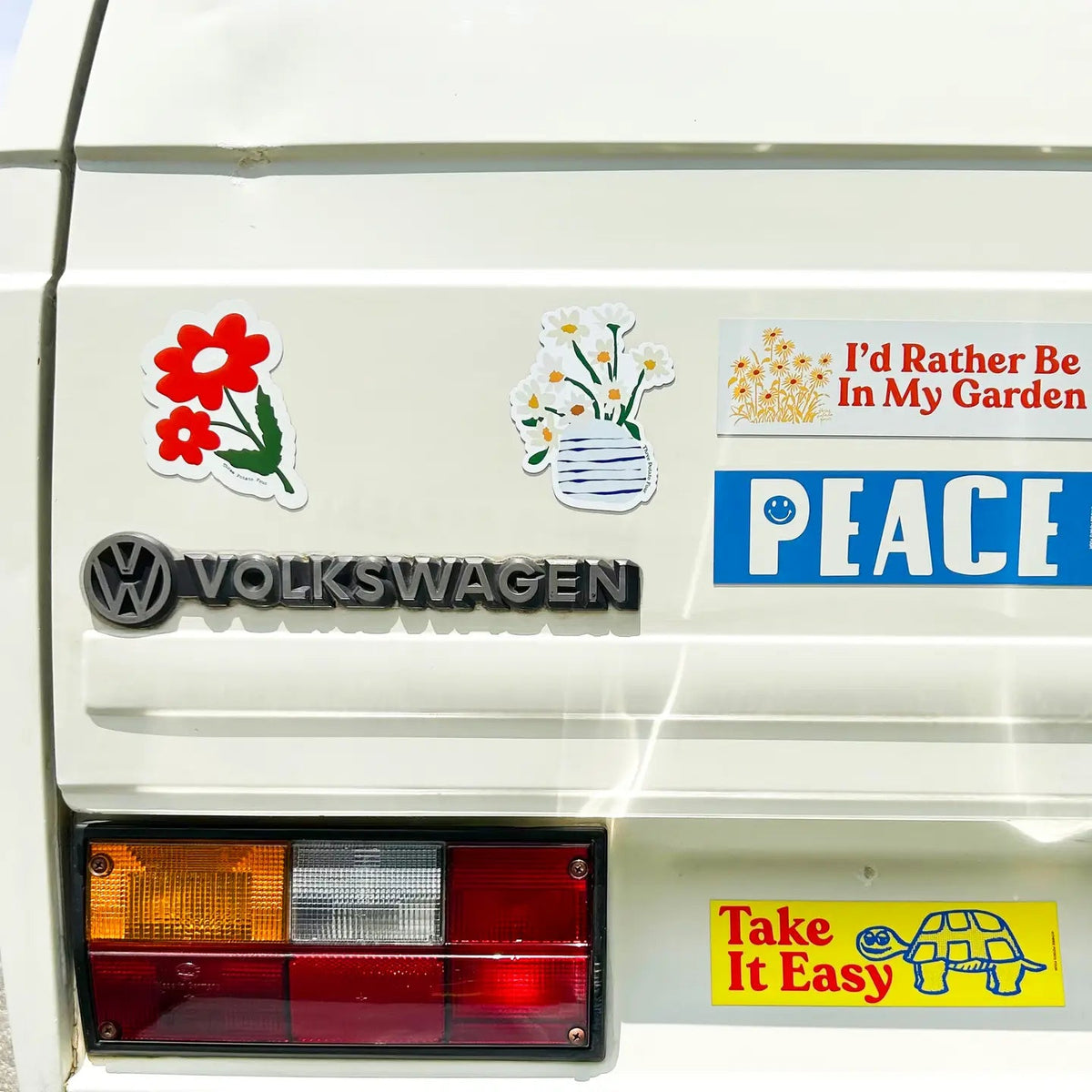 Back of white van with colorful flower stickers, Three Potato Four 3P4 Peace Camper Van Magnet, retro road trip style.