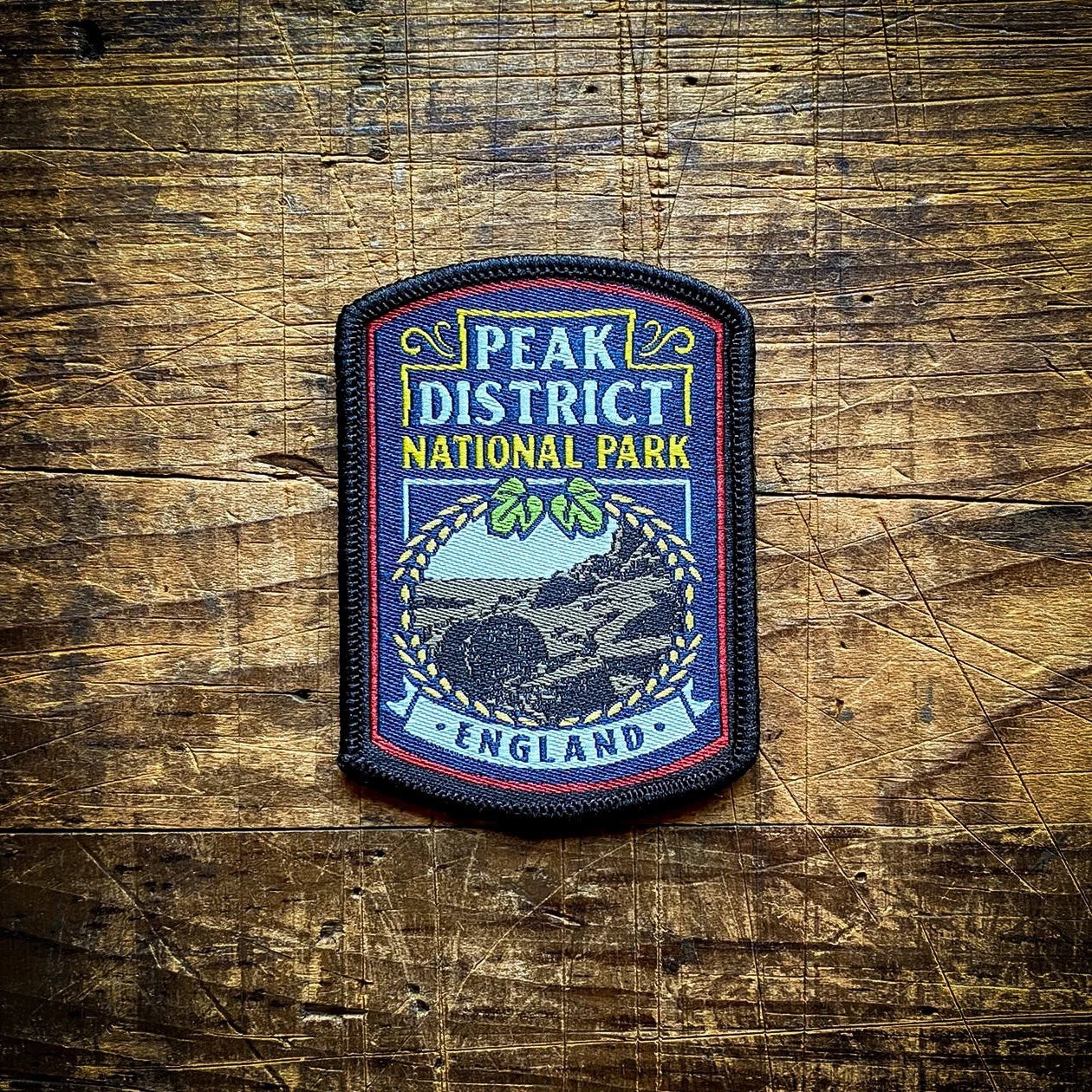 Forager Provisions LTD Peak District National Park embroidered patch with landscape design on a wooden background.