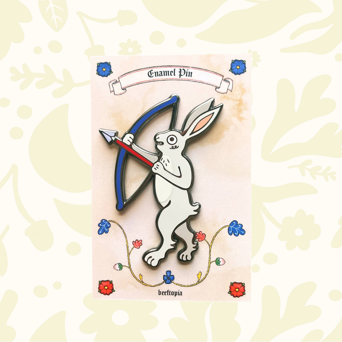 Forager Provisions LTD Beeftopia enamel pin featuring a white rabbit archer with a blue bow on a floral backing card.