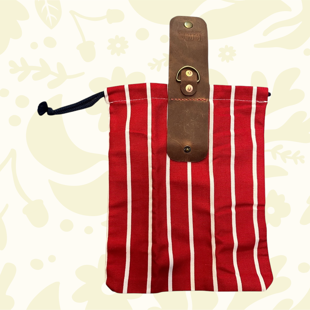 Forager Provisions LTD red Forager Bag with brown leather flap, brass snap, on a pale patterned background; stylish gear.