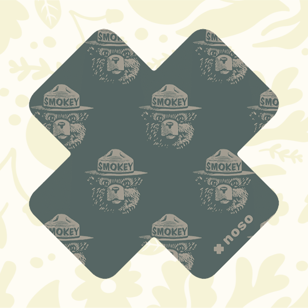 Forager Provisions LTD Smokey Bear woodblock cross repair patch in dark green with a repeating bear face pattern.