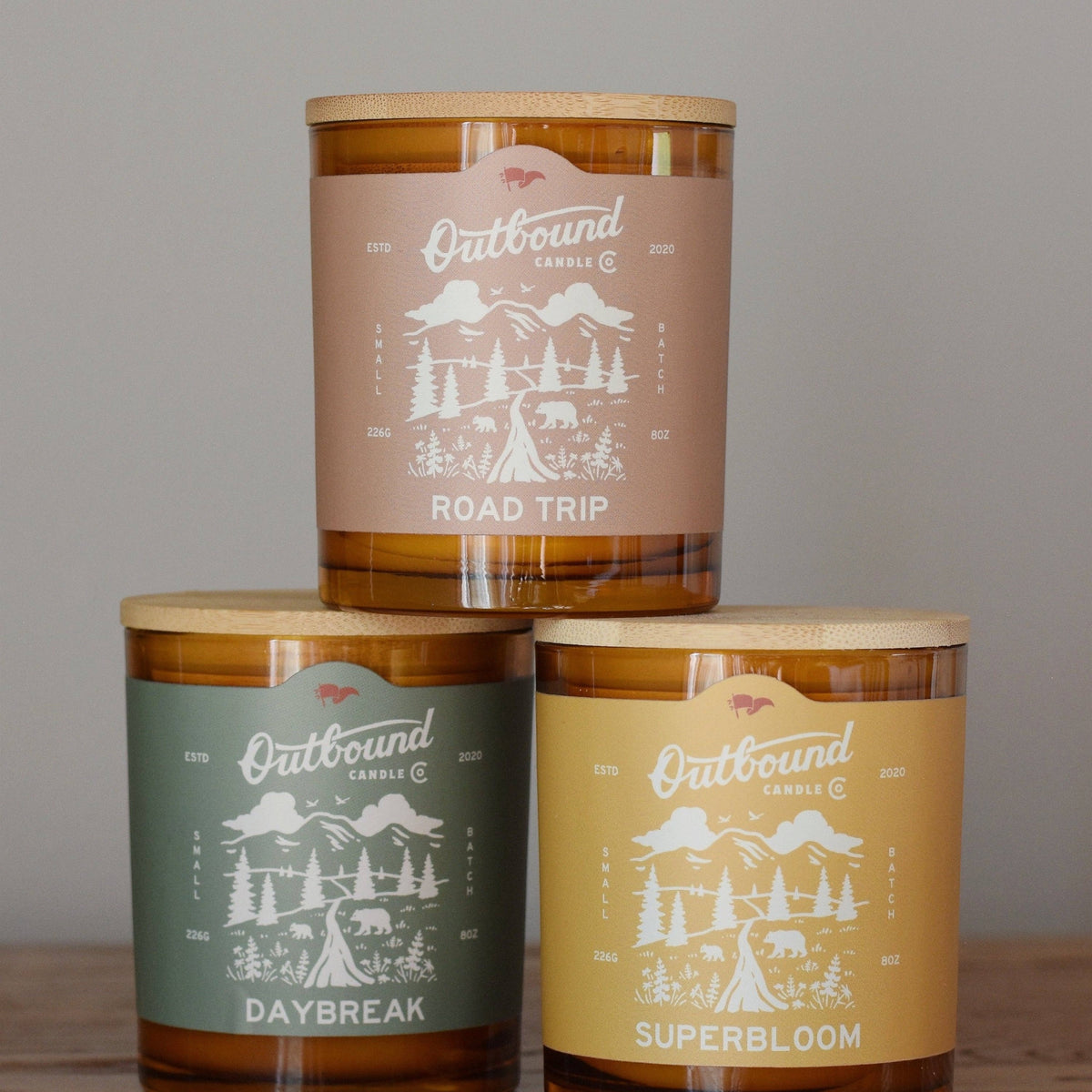 Forager Provisions LTD soy wax candles in amber glass jars with bamboo lids, featuring Road Trip, Daybreak, and Superbloom labels.