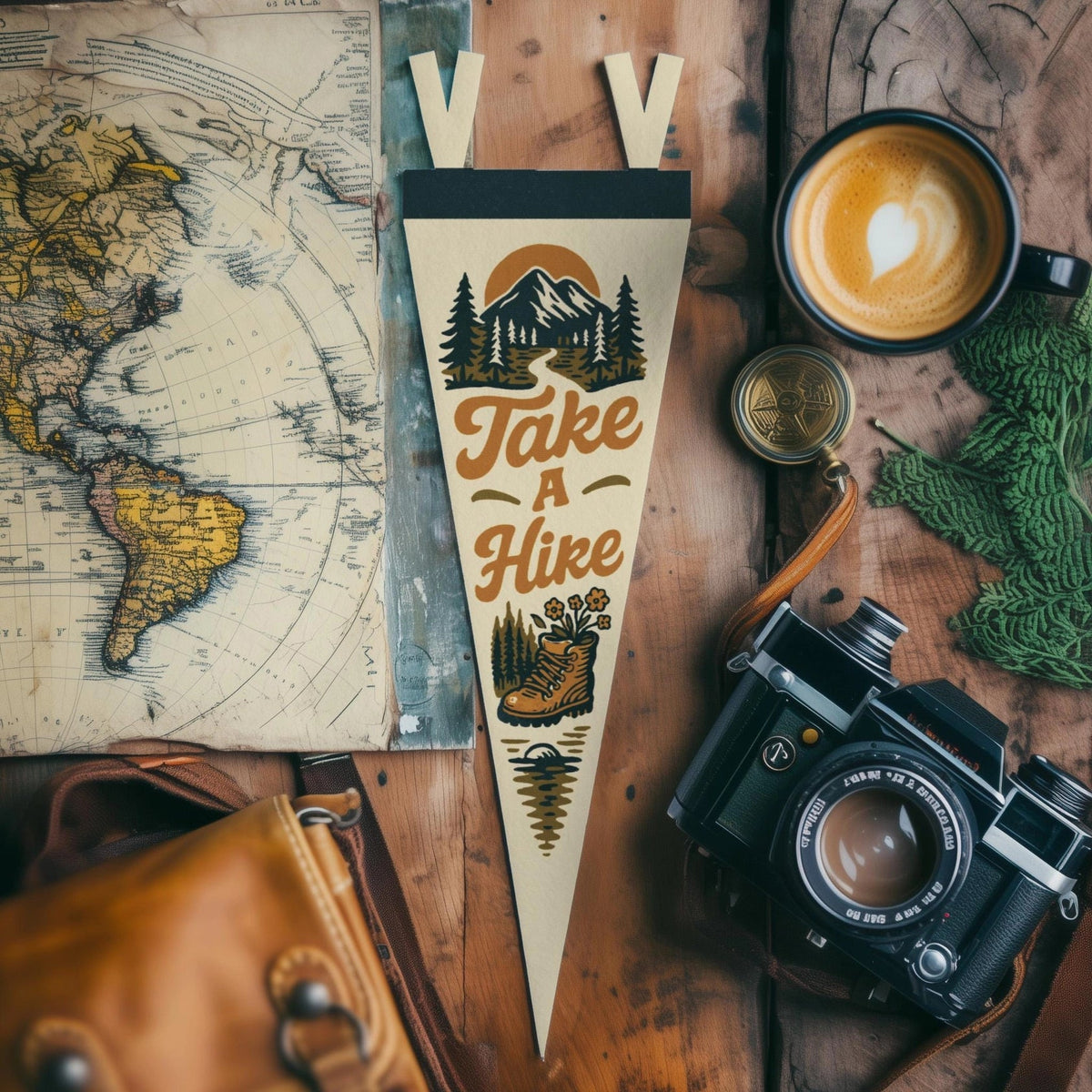 Forager Provisions LTD Benoit Design Co Take A Hike felt pennant on a wooden desk with a vintage camera and map.