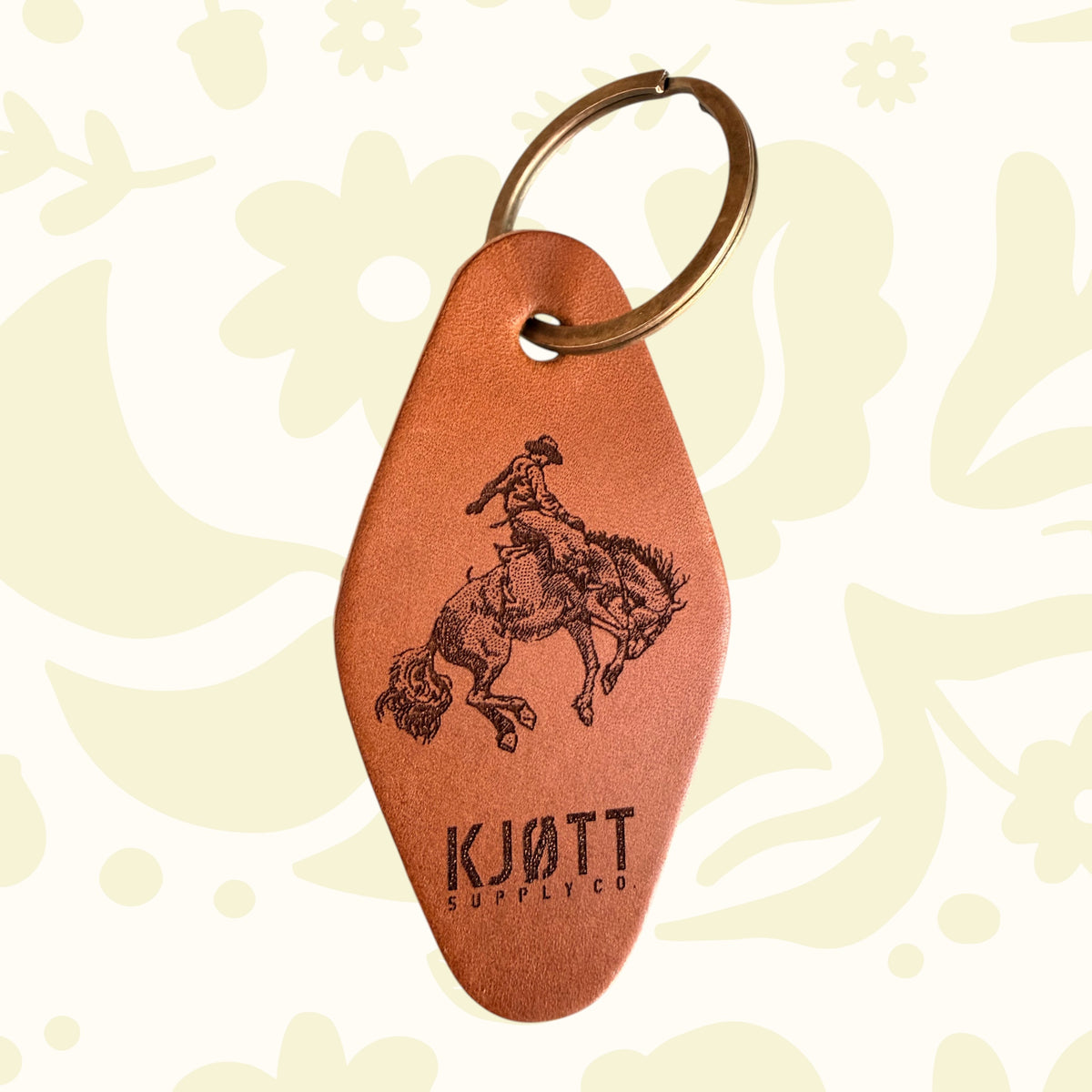 Forager Provisions LTD Kjøtt Supply Co tan leather motel keyring with a cowboy design and metal ring.