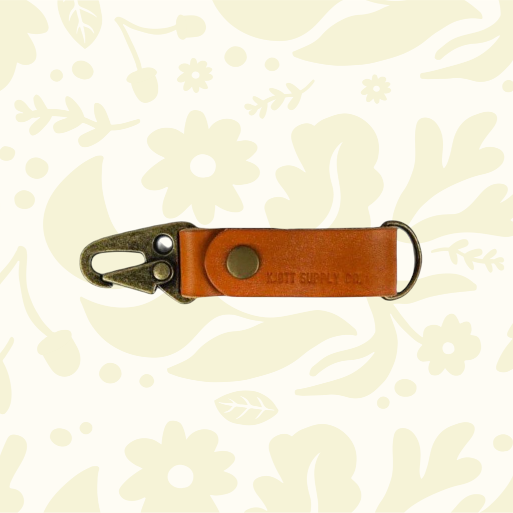 Kjøtt Forager Provisions Leather Key Fob 2026 new colors on floral leaf background, premium leather keychain accessory.