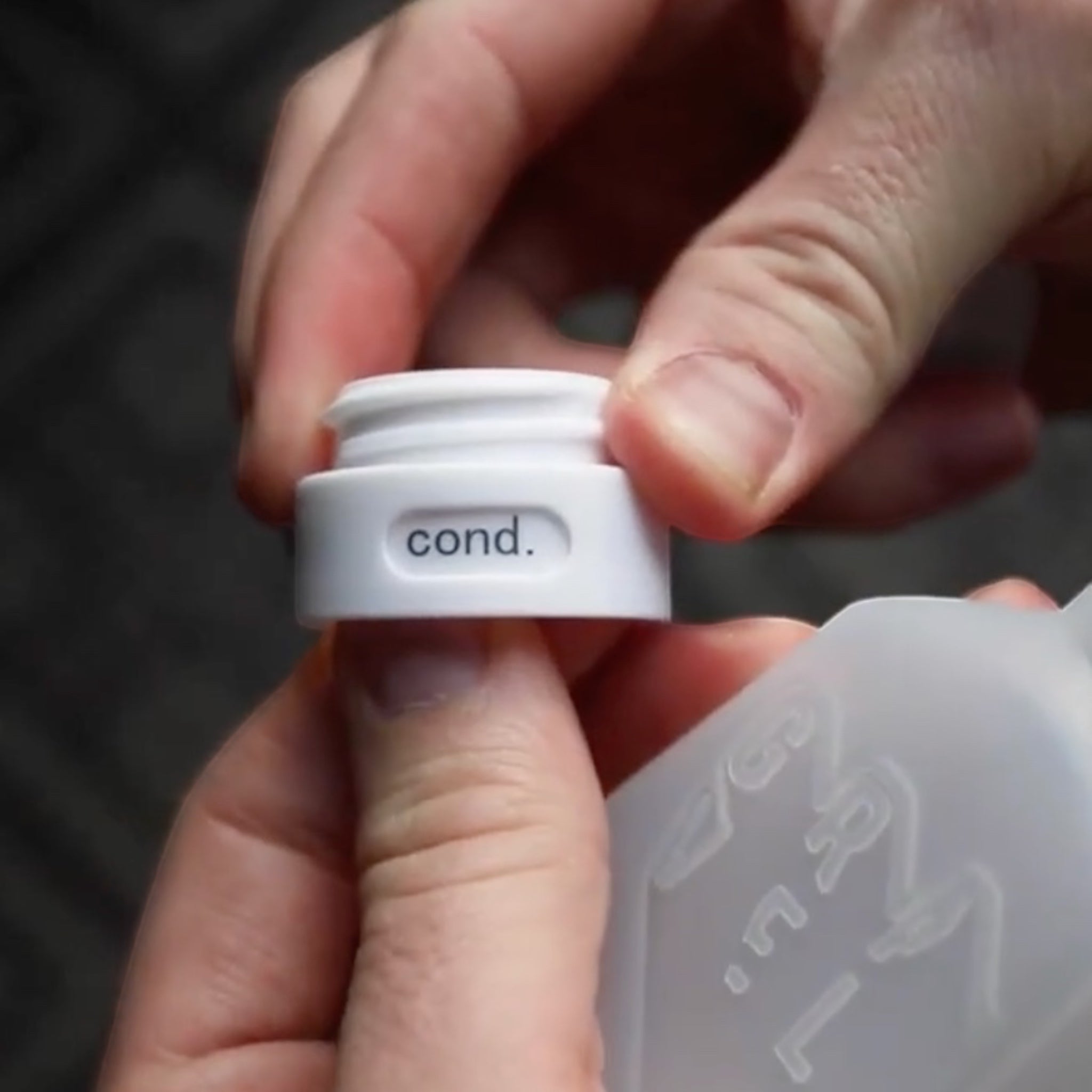 Forager Provisions LTD Gravel Outdoors travel bottle cap labeled cond. for conditioner, held in hands.