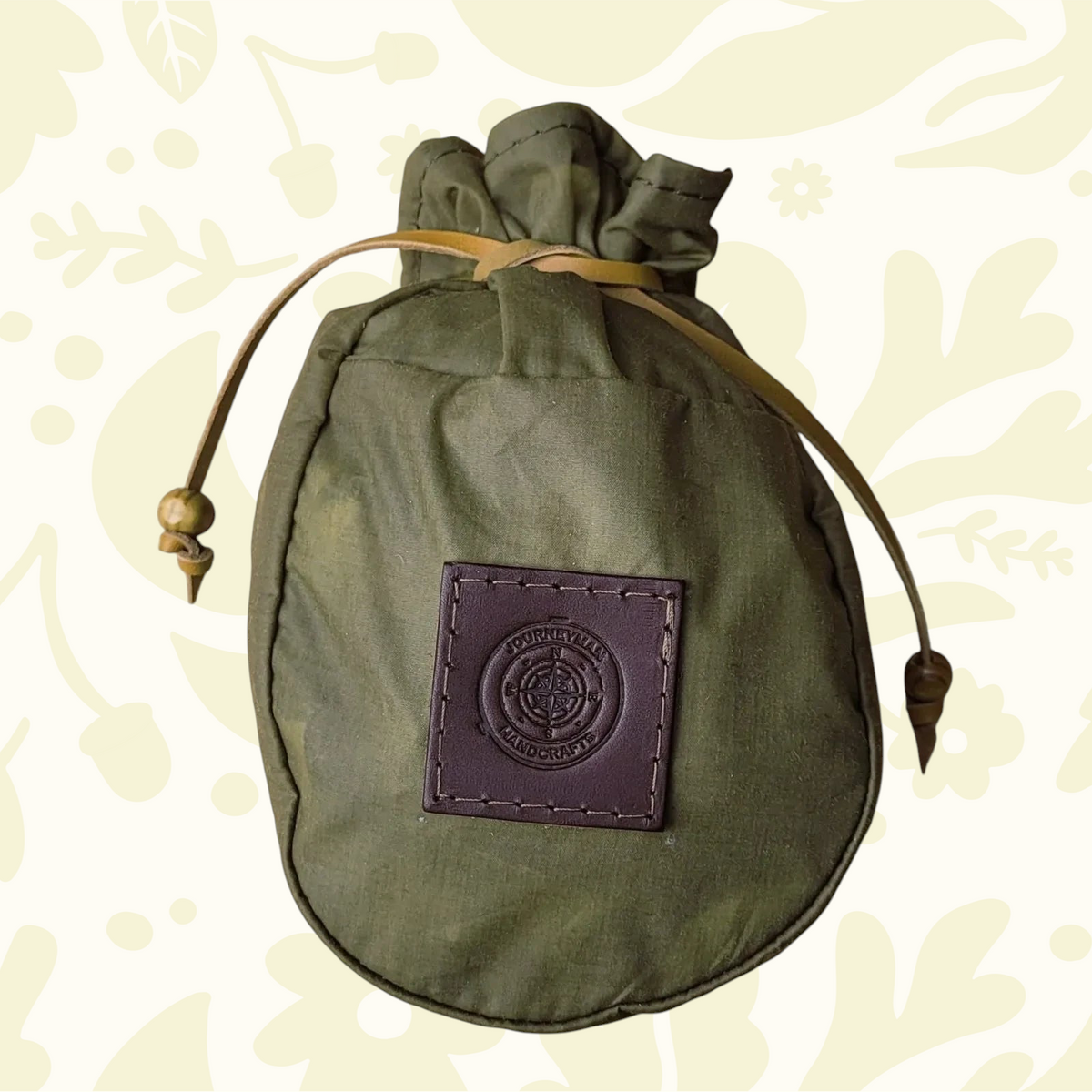 Journeyman Craft Khaki Green Waxed Canvas Coffee Pouch for camping, durable gear on a patterned background, eco-friendly.
