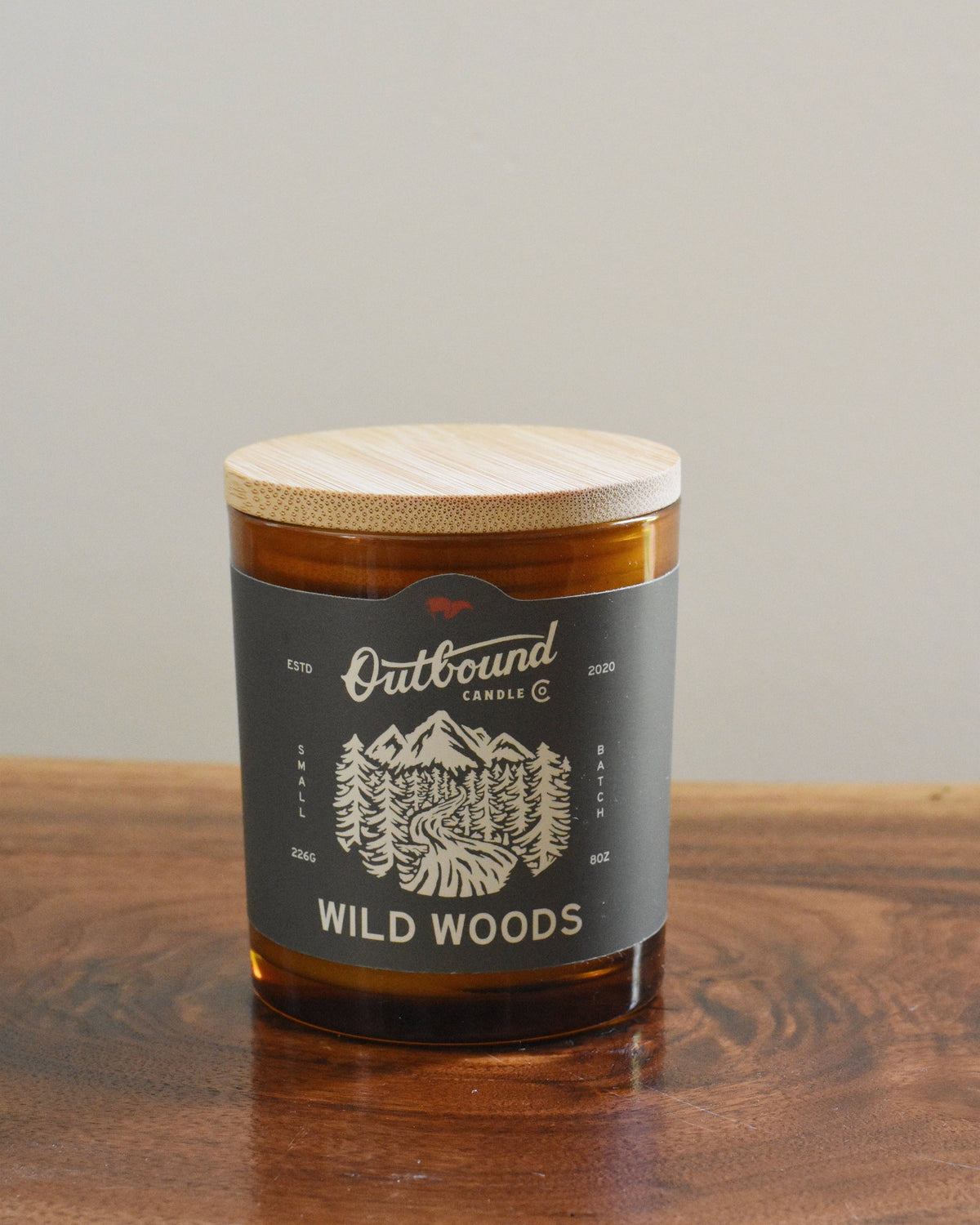 Forager Provisions LTD Outbound Candle Co Wild Woods soy candle in amber glass jar with bamboo lid on wooden surface
