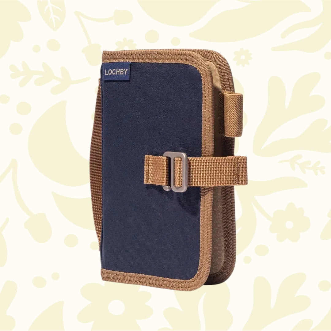 Lochby Mini Field Journal Diary Nautical navy brown pouch with buckle, zippered case stands upright on floral print surface.